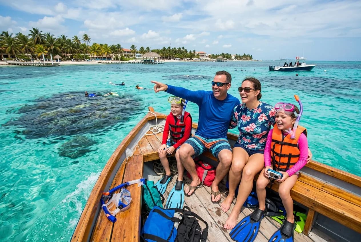 Crystal clear water over the Belize Barrier Reef with tropical fish and coral visible below a family snorkeling boat
